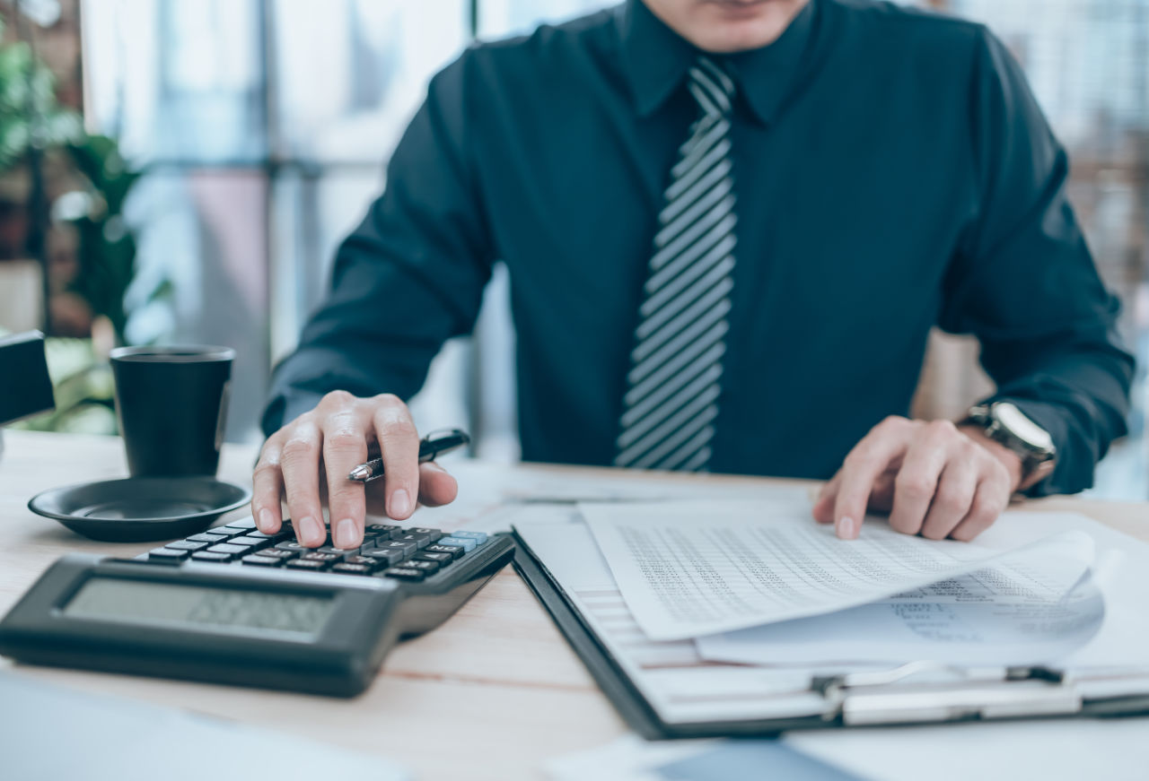 Accountant working on calculator to calculate company accounts
